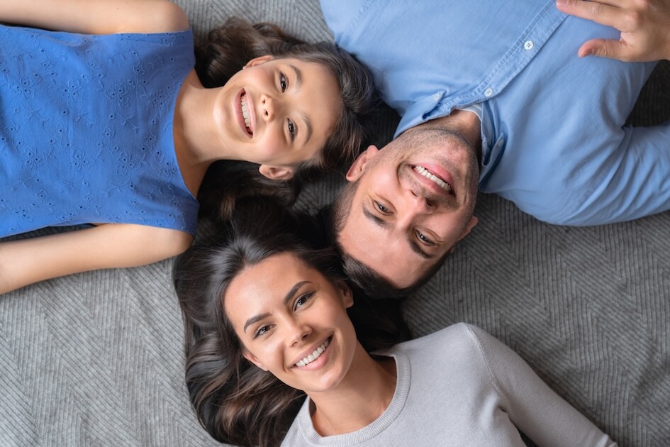 Una familia feliz tirada en el suelo y sonriendo.